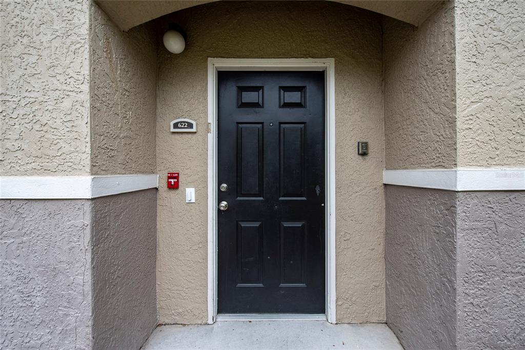 A black front door with a number plate is set into a beige stucco exterior wall — 6548 SWISSCO DRIVE UNIT 622, ORLANDO, FL