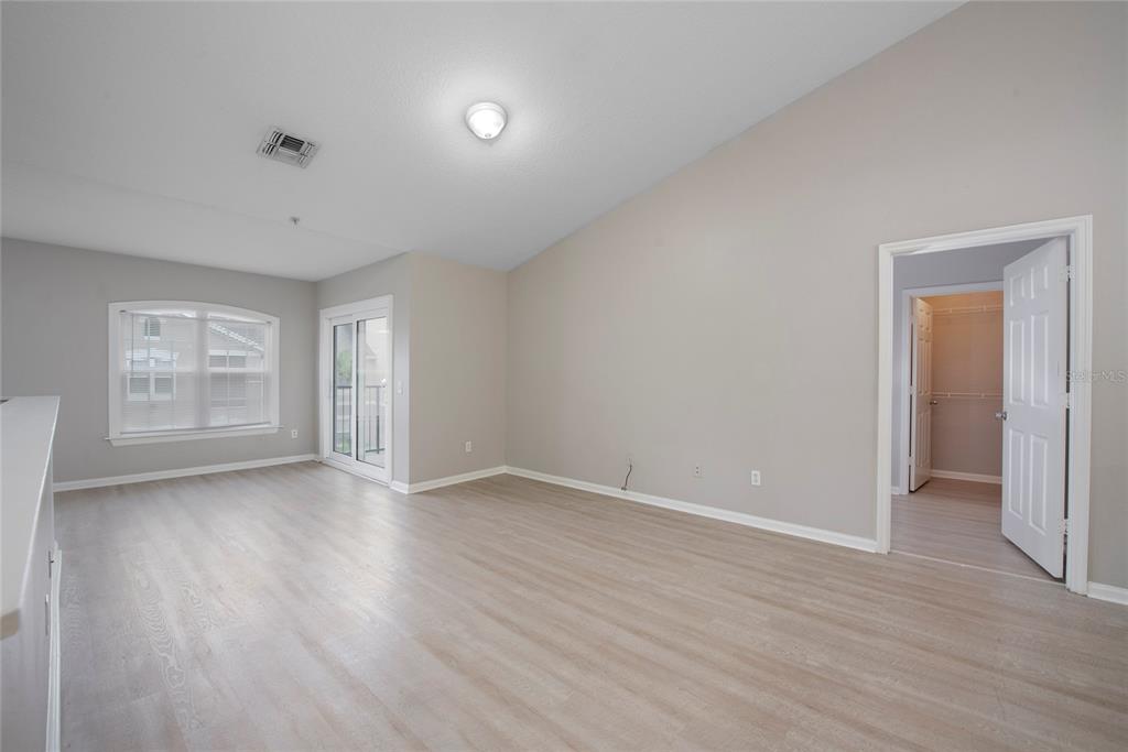 An empty room with light wood-look flooring, a vaulted ceiling, and a walk-in closet — 6548 SWISSCO DRIVE UNIT 622, ORLANDO, FL