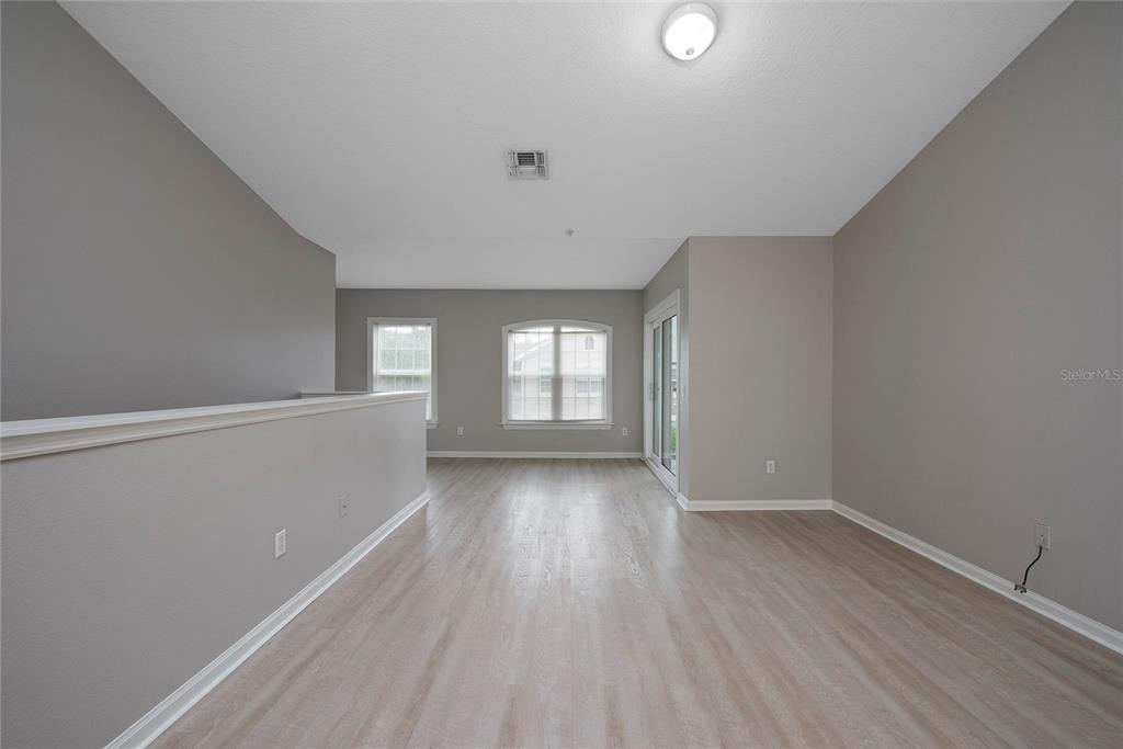 An empty room with gray walls, light wood-look flooring, and a sliding glass door — 6548 SWISSCO DRIVE UNIT 622, ORLANDO, FL