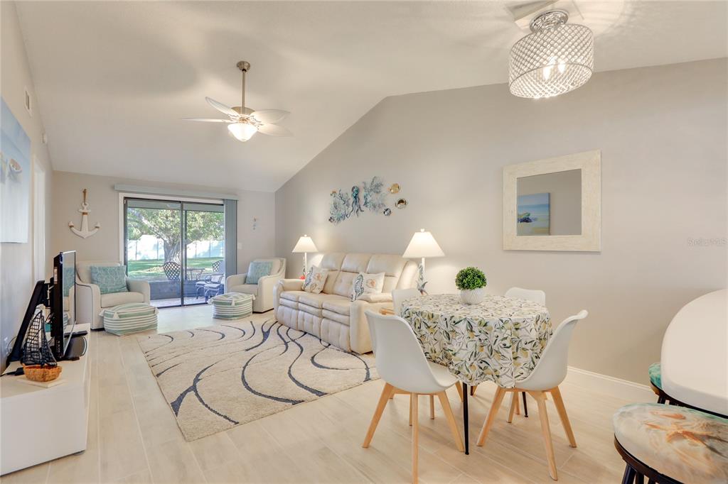 A living and dining area features a vaulted ceiling, tile floors, and coastal-themed decor — 6010 36TH AVENUE CIRCLE W, BRADENTON, FL