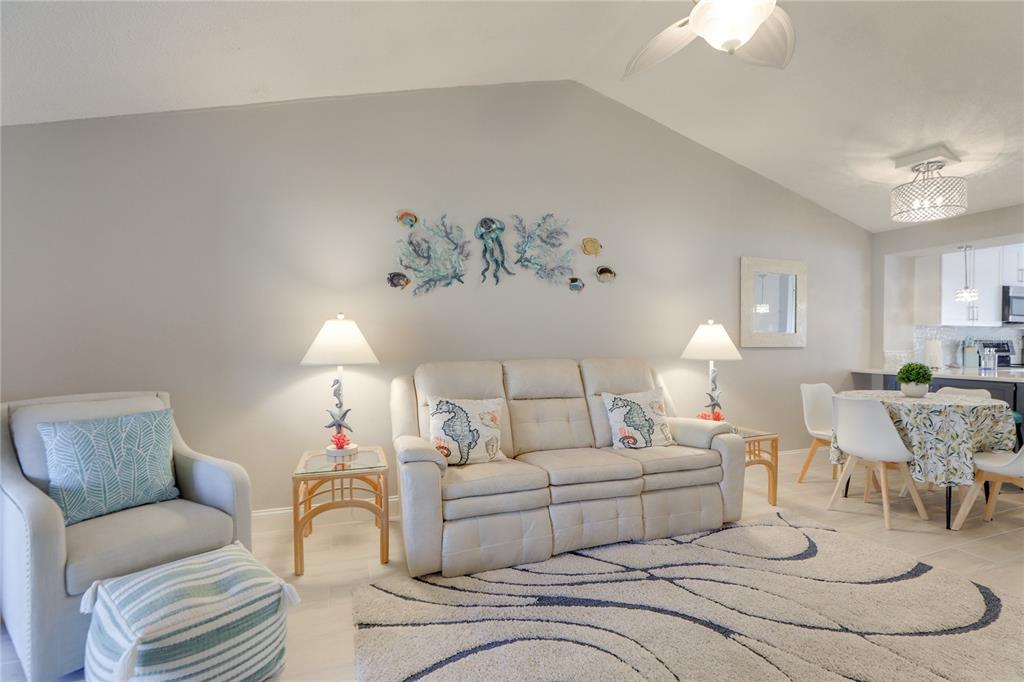 A living room features a beige sofa, a patterned area rug, and coastal wall decor — 6010 36TH AVENUE CIRCLE W, BRADENTON, FL
