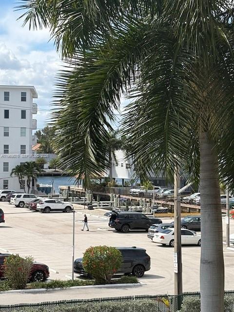 A palm tree frames a view of a parking lot with cars and a waterfront building — 3181 S Ocean Dr # 304, Hallandale Beach FL 33009, HALLANDALE BEACH, FL