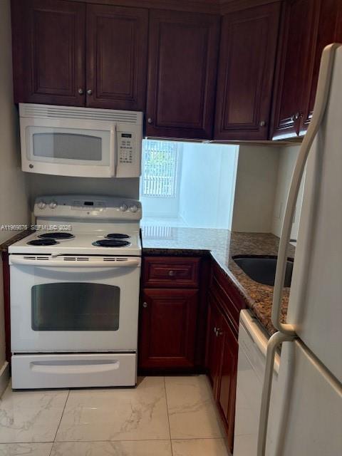 A kitchen features dark wood cabinets, white appliances, and granite countertops over light tile floors — 3181 S Ocean Dr # 304, Hallandale Beach FL 33009, HALLANDALE BEACH, FL