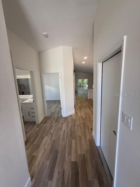 A hallway with wood-look flooring leads to an open living area and a bathroom — 108 SUNDANCE COURT, WINTER SPRINGS, FL