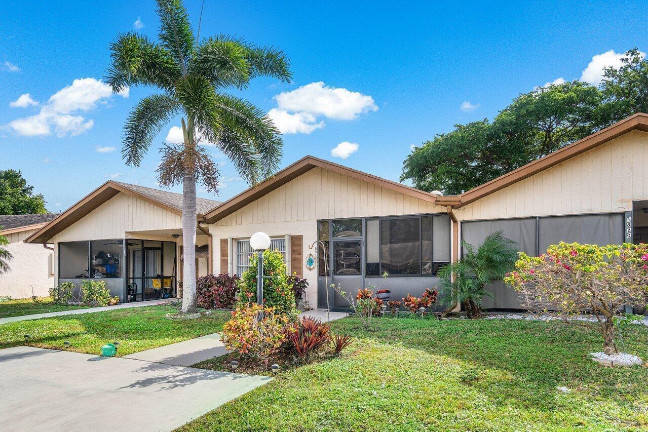 A single-story duplex with beige siding, screened-in porches, and a tall palm tree in front — 5814 Doris Court, Delray Beach FL 33484, DELRAY BEACH, FL