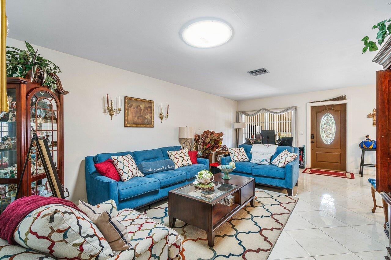 A living room features two blue sofas, a coffee table, and a patterned area rug — 5814 Doris Court, Delray Beach FL 33484, DELRAY BEACH, FL