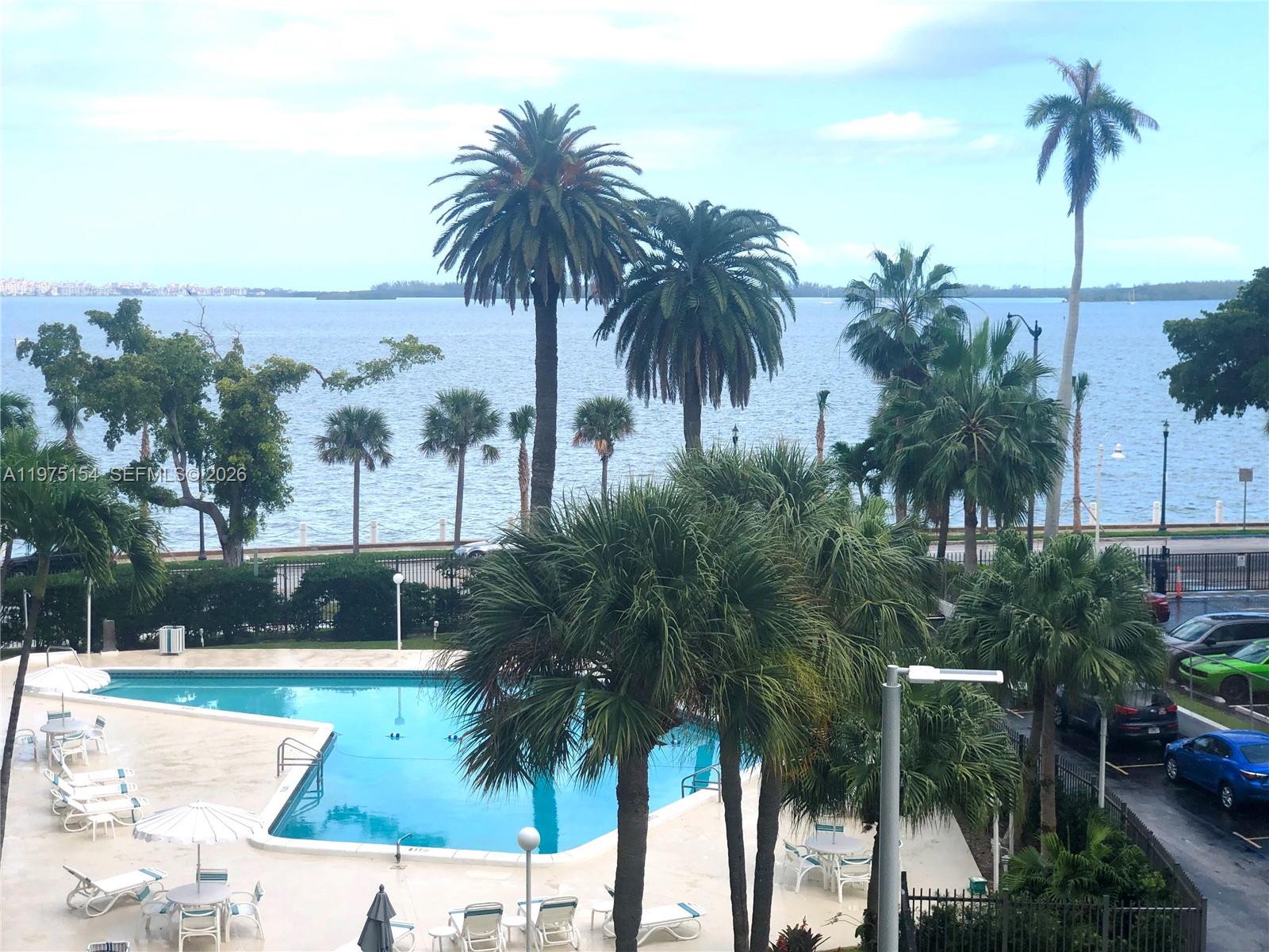 An outdoor swimming pool is surrounded by palm trees with a view of the ocean — 1408 Brickell Bay Dr # 404, Miami FL 33131, MIAMI, FL