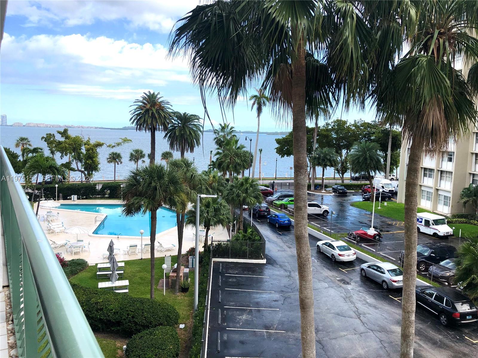 An elevated view shows a swimming pool, palm trees, a parking lot, and a waterfront — 1408 Brickell Bay Dr # 404, Miami FL 33131, MIAMI, FL