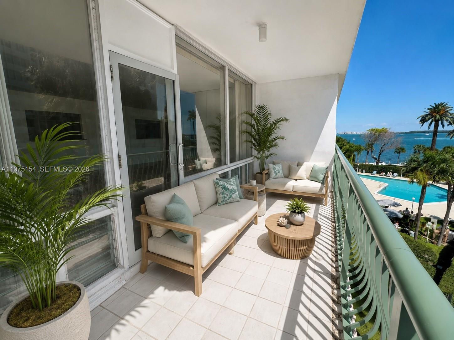 A balcony features two sofas, a coffee table, potted plants, and a view of the ocean — 1408 Brickell Bay Dr # 404, Miami FL 33131, MIAMI, FL
