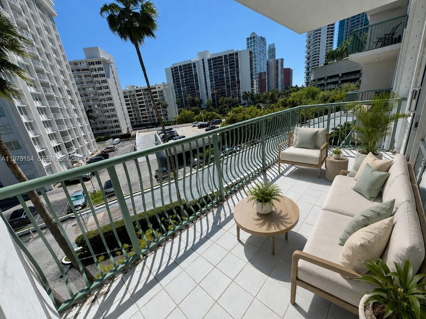 A balcony with outdoor furniture overlooks a parking lot and surrounding high-rise buildings — 1408 Brickell Bay Dr # 404, Miami FL 33131, MIAMI, FL