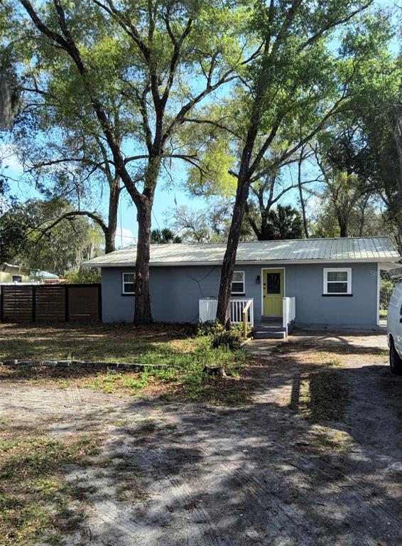 A single-story gray house with a metal roof and a yellow front door — 1412 E VOORHIS AVENUE, DELAND, FL