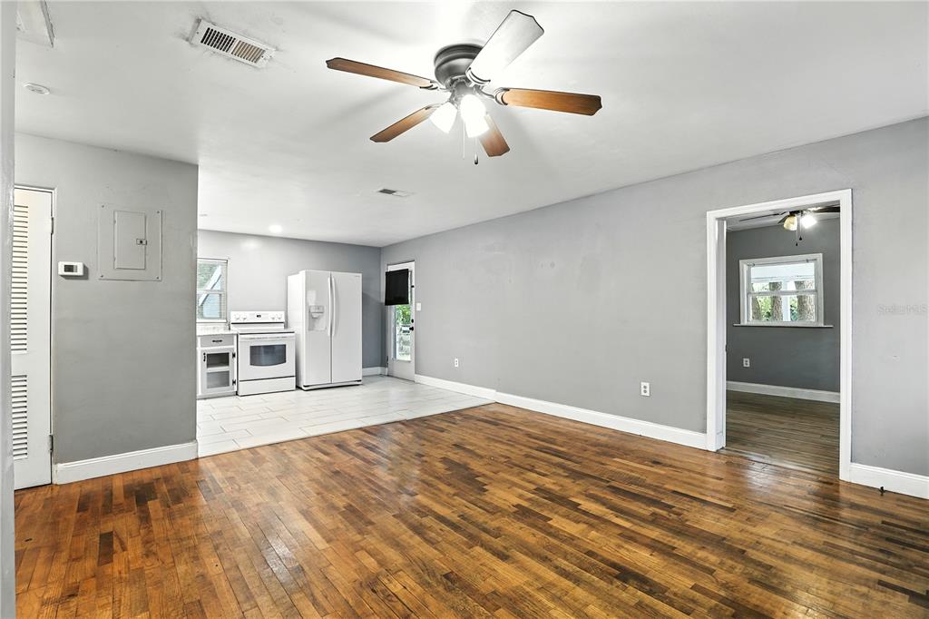 A living room with hardwood floors transitions into a tiled kitchen area with white appliances — 1412 E VOORHIS AVENUE, DELAND, FL