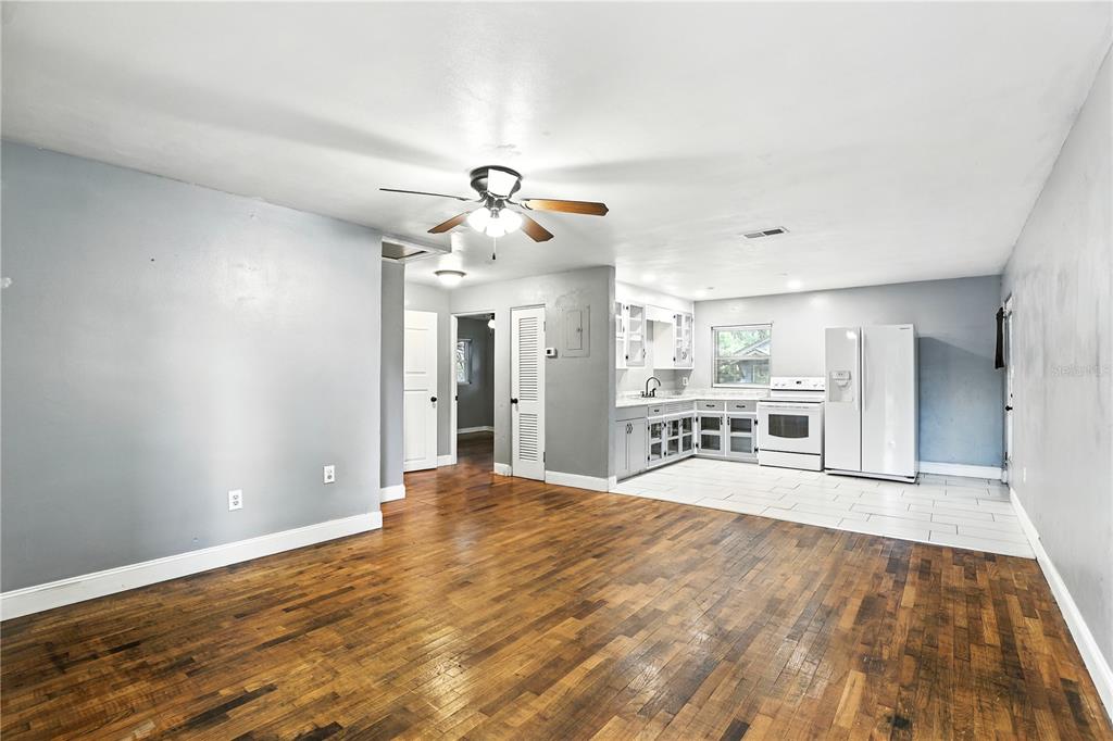 An open-concept living room with hardwood floors transitions into a tiled kitchen area — 1412 E VOORHIS AVENUE, DELAND, FL