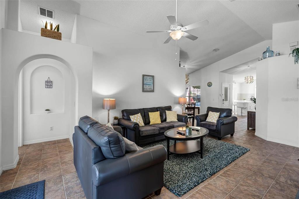 A living room features dark leather furniture, a round coffee table, and tile flooring — 8065 INDIAN CREEK BOULEVARD, KISSIMMEE, FL