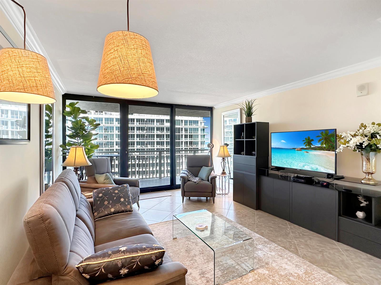 A living room features a grey sofa, glass coffee table, and a balcony with city views — 3000 N Ocean Drive # b, Singer Island FL 33404, SINGER ISLAND, FL