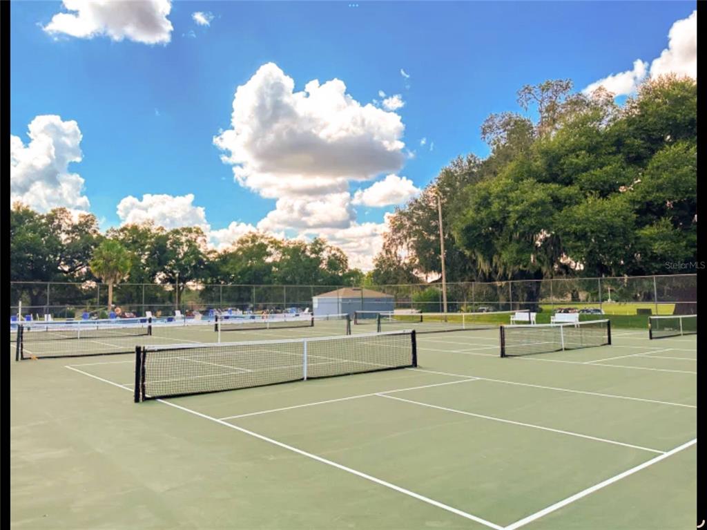 A view of multiple outdoor tennis courts with nets and a chain-link fence — NW 109TH PLACE, ALACHUA, FL
