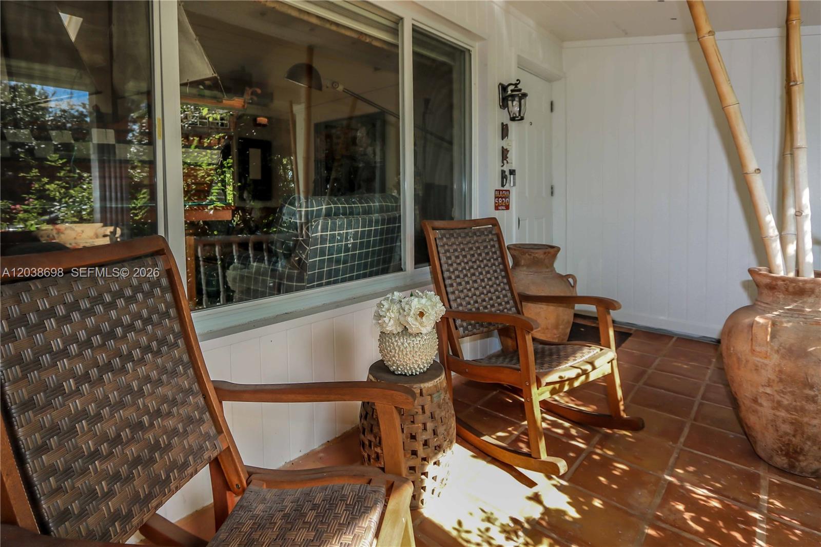 A covered porch features two rocking chairs, a small side table, and large decorative pots — 1251 Buchanan St, Hollywood FL 33019, HOLLYWOOD, FL