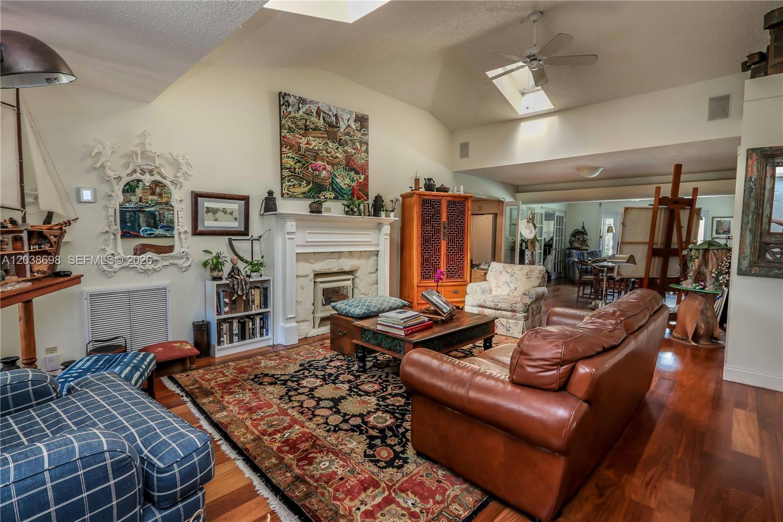A living room features a fireplace, leather sofa, patterned rug, and vaulted ceilings with skylights — 1251 Buchanan St, Hollywood FL 33019, HOLLYWOOD, FL