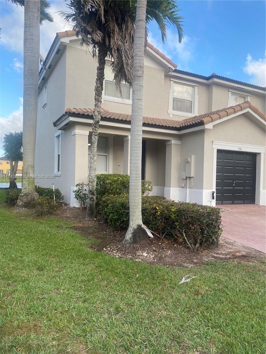 A two-story stucco house with a black garage door and palm trees in the front — 991 NE 42nd Ave # 0, Homestead FL 33033, HOMESTEAD, FL
