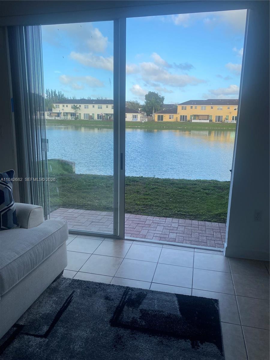A living room with tile floors and a sliding glass door overlooking a lake — 991 NE 42nd Ave # 0, Homestead FL 33033, HOMESTEAD, FL