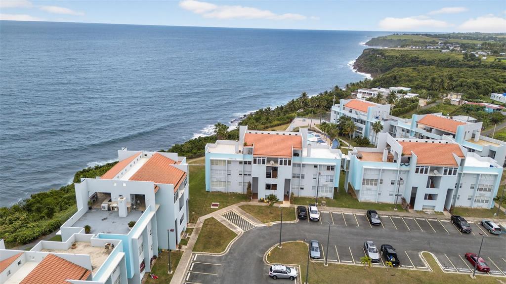 An aerial view shows several multi-story apartment buildings with orange roofs near the ocean — Paraíso del Atlántico CARR. 4485 Apt. 307, QUEBRADILLAS, PR