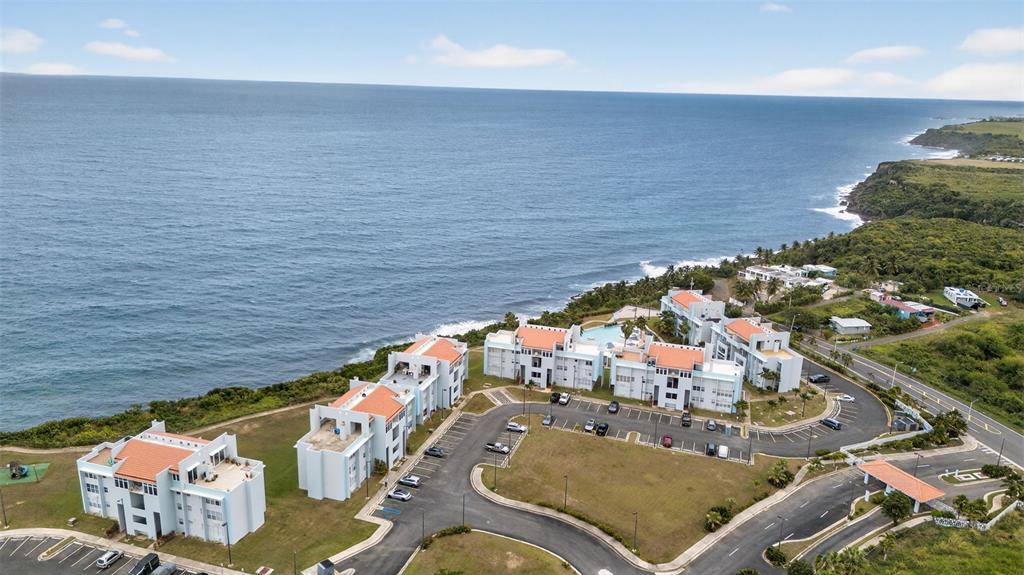 An aerial view shows a coastal apartment complex with light blue buildings and red roofs — Paraíso del Atlántico CARR. 4485 Apt. 307, QUEBRADILLAS, PR