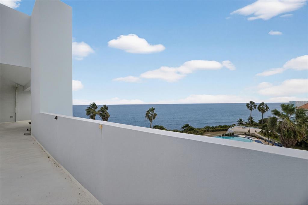A white balcony overlooks the ocean, palm trees, and a swimming pool below — Paraíso del Atlántico CARR. 4485 Apt. 307, QUEBRADILLAS, PR