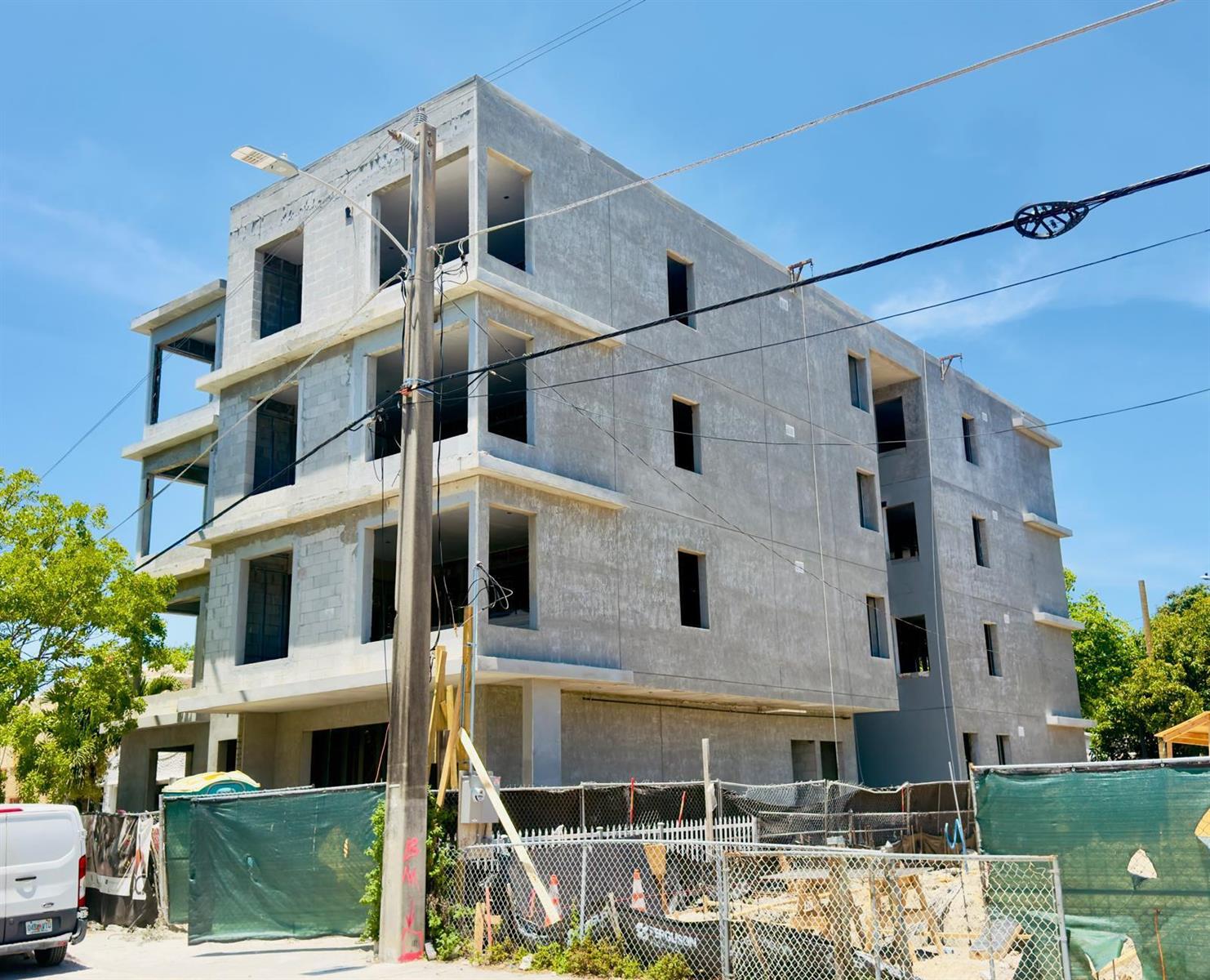 A multi-story concrete building under construction stands behind a chain-link fence on a sunny day — 259 NW 33rd Street # 2, Miami FL 33127, MIAMI, FL