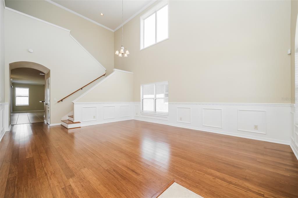 A spacious living room with high ceilings, hardwood floors, white wainscoting, and a staircase — 7318 FOREST MERE DRIVE, RIVERVIEW, FL