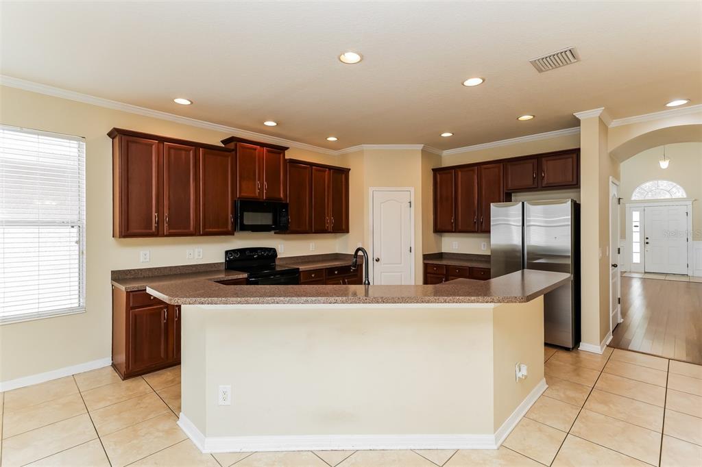 A kitchen with dark wood cabinets, stainless steel appliances, and a breakfast bar island — 7318 FOREST MERE DRIVE, RIVERVIEW, FL
