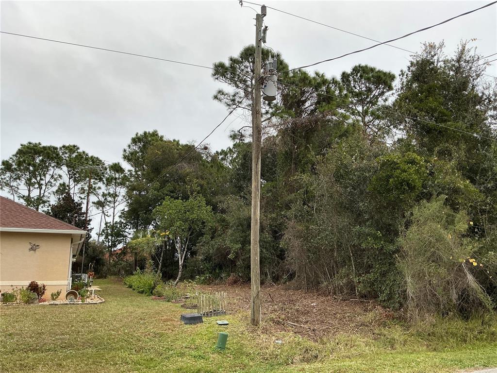 A utility pole with a transformer stands in a grassy yard next to a house — 12 FAYY LANE, PALM COAST, FL
