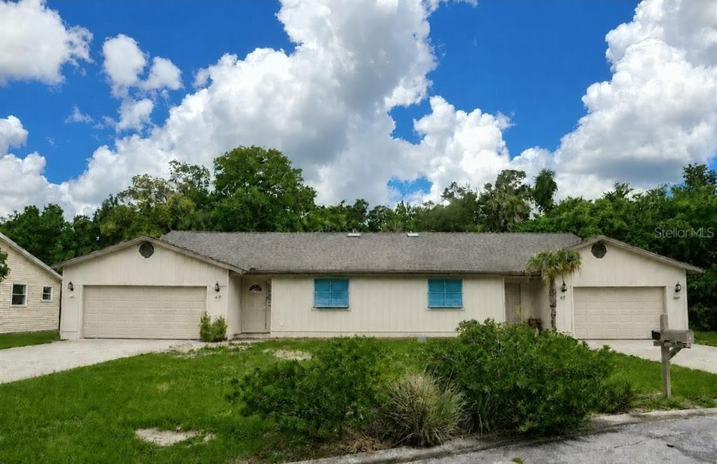 A single-story duplex with two garages, light-colored siding, and blue shutters under a cloudy sky — 47 & 49 SANDPIPER CIRCLE UNIT 47 & 49, ORMOND BEACH, FL