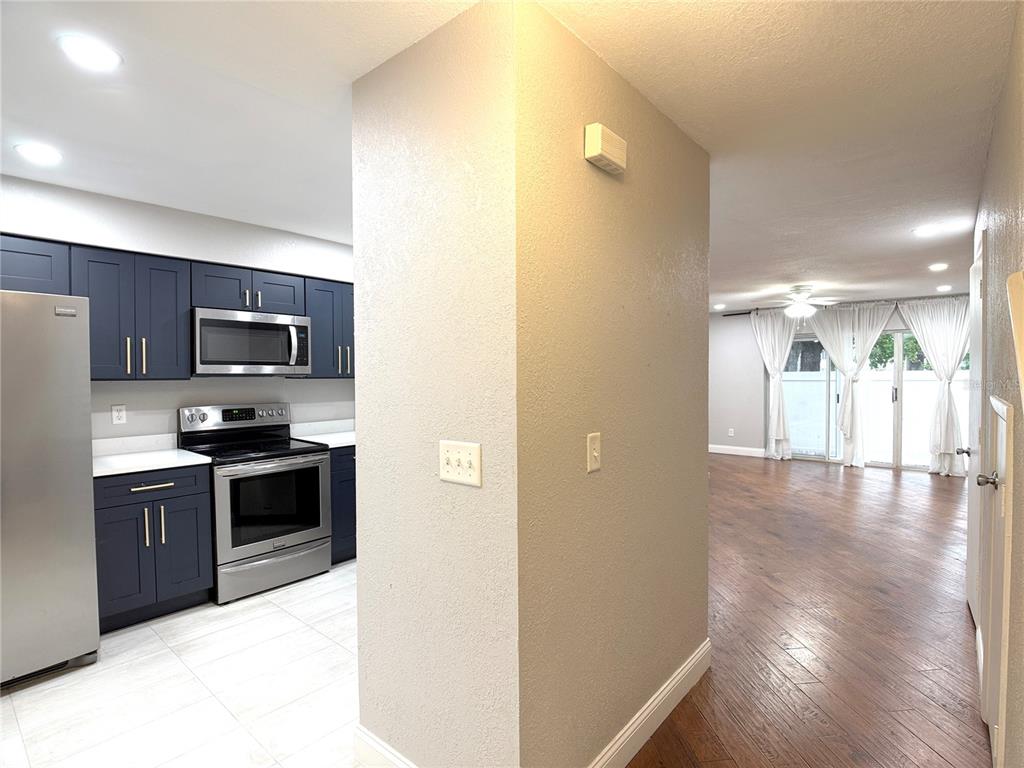 A kitchen with dark blue cabinets and stainless steel appliances opens to a living area — 4815 WALDEN CIRCLE UNIT 75, ORLANDO, FL