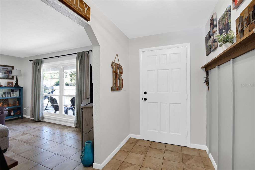 An entryway with a white door, tile flooring, and a decorative letter B on the wall — 317 NW 7TH STREET, WILLISTON, FL