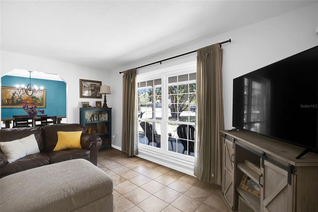 A living room features tile floors, a brown leather sofa, and a large television console — 317 NW 7TH STREET, WILLISTON, FL
