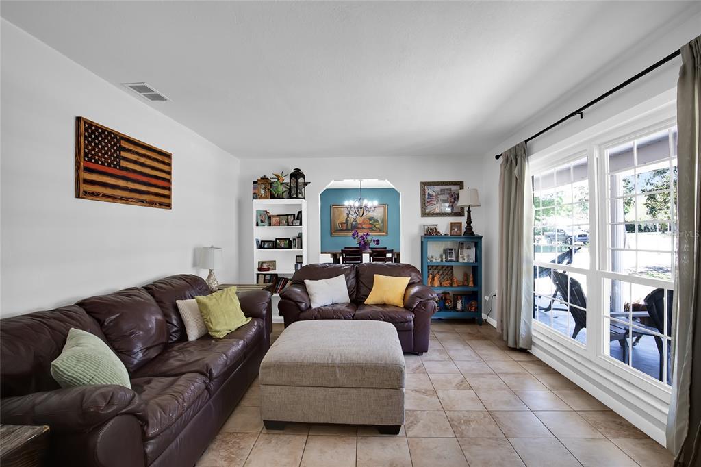 A living room features brown leather sofas, a large ottoman, and tile flooring — 317 NW 7TH STREET, WILLISTON, FL