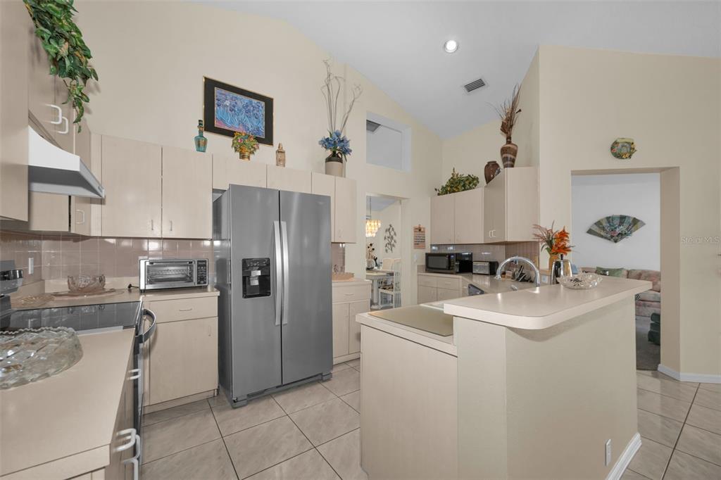 A kitchen with light-colored cabinets, stainless steel appliances, and a breakfast bar — 7405 EVESBOROUGH LANE, NEW PORT RICHEY, FL