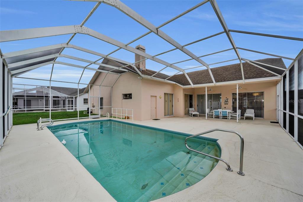 A screened-in swimming pool and patio area behind a single-story house — 7405 EVESBOROUGH LANE, NEW PORT RICHEY, FL