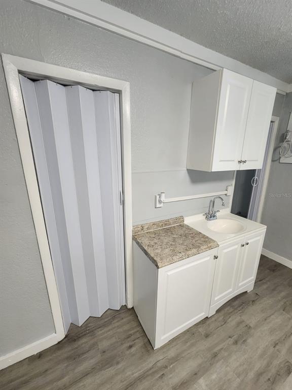 A small kitchenette features white cabinets, a laminate countertop, and a sink against a wall — 407 S JUPITER AVENUE UNIT 7, CLEARWATER, FL