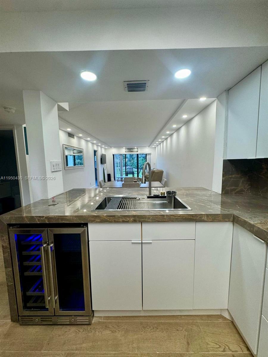 A kitchen island with a sink and wine cooler faces a dining area — 10044 S Ocean dr # 105, Jensen Beach FL 34957, JENSEN BEACH, FL