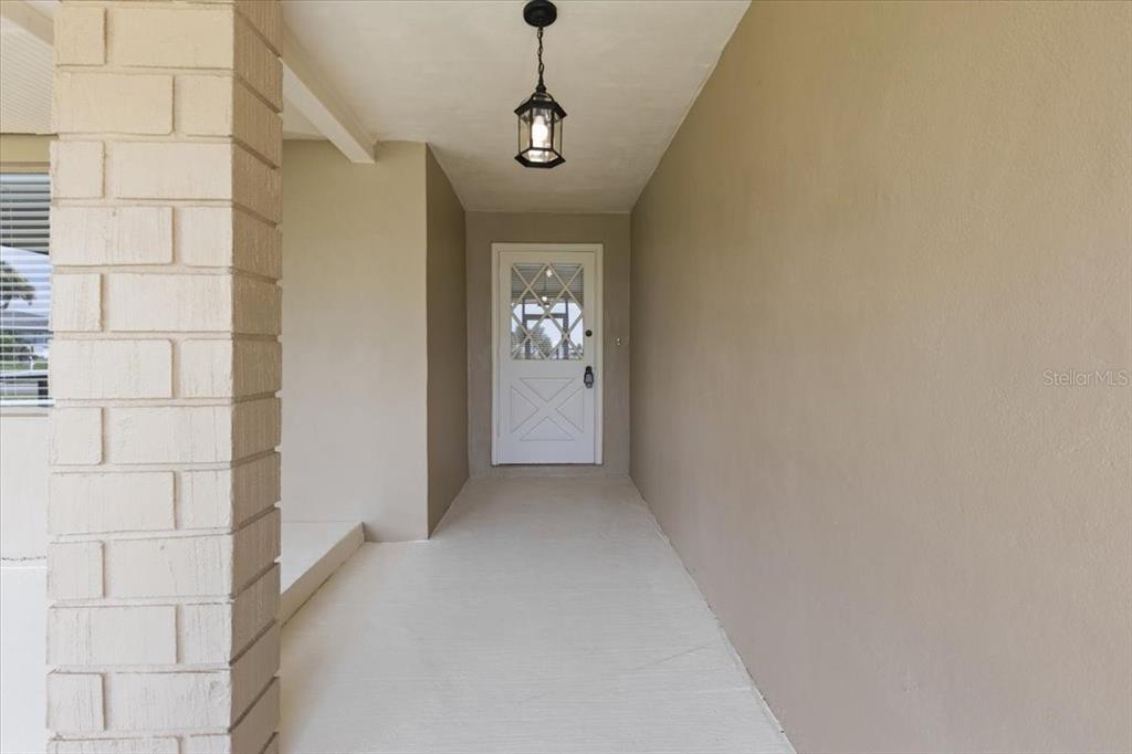 A covered entryway features a white door, a hanging lantern, and a brick pillar — 267 ANNAPOLIS LANE, ROTONDA WEST, FL