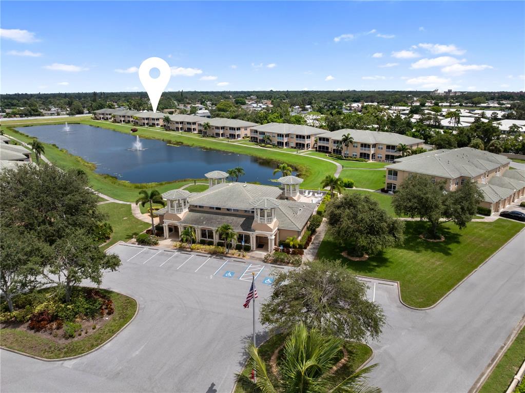 An aerial view shows a community clubhouse and apartment buildings surrounding a central pond — 6616 7TH AVENUE CIRCLE W UNIT 1311, BRADENTON, FL