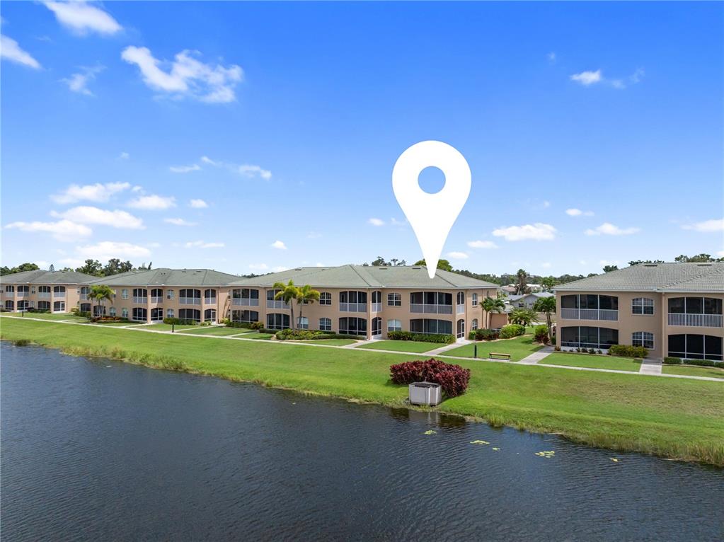 An exterior view of a multi-story apartment building situated along a lake — 6616 7TH AVENUE CIRCLE W UNIT 1311, BRADENTON, FL