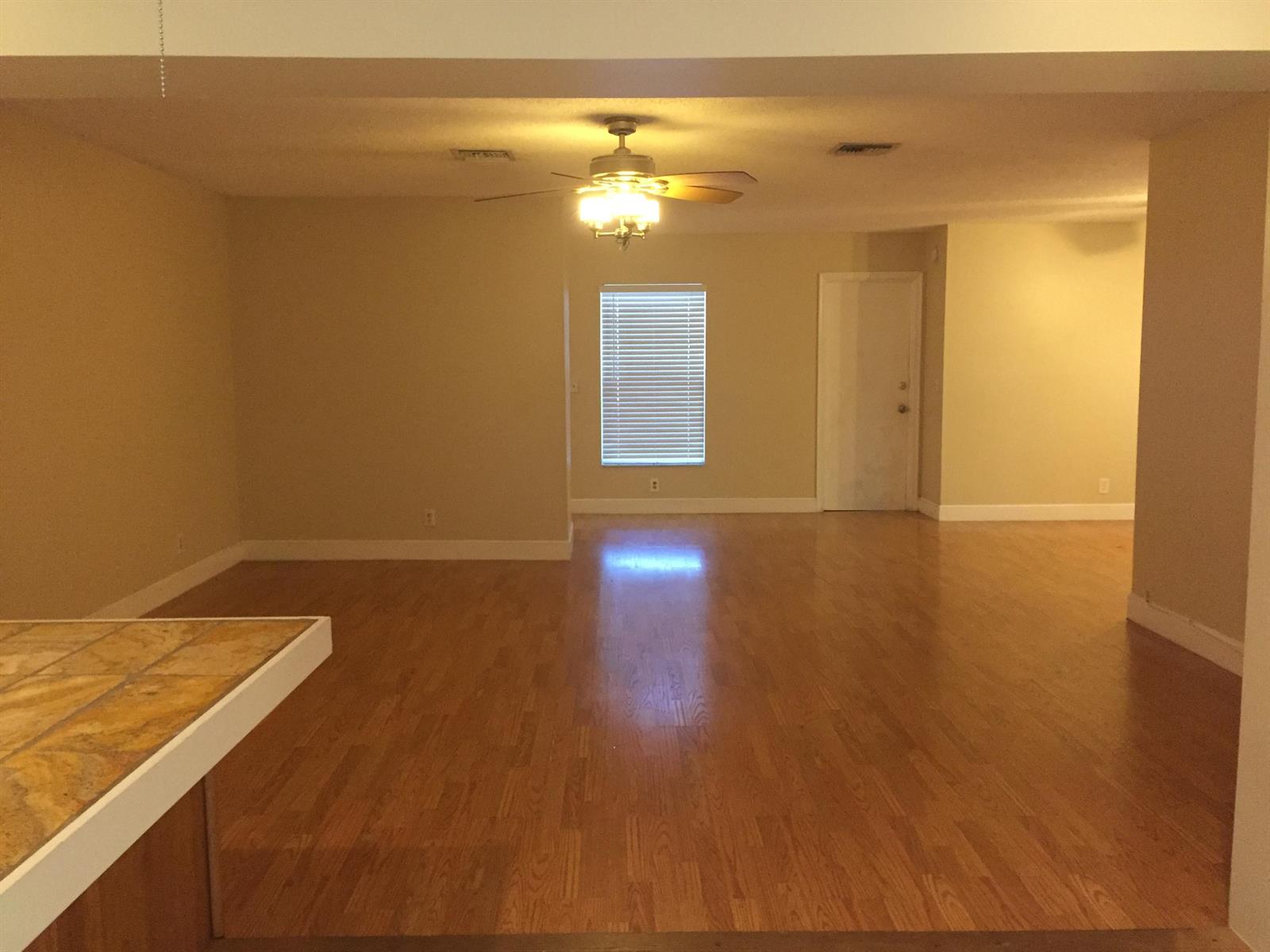 An empty living room features hardwood floors, a ceiling fan, and a single window — 22447 SW 56th Avenue, Boca Raton FL 33433, BOCA RATON, FL