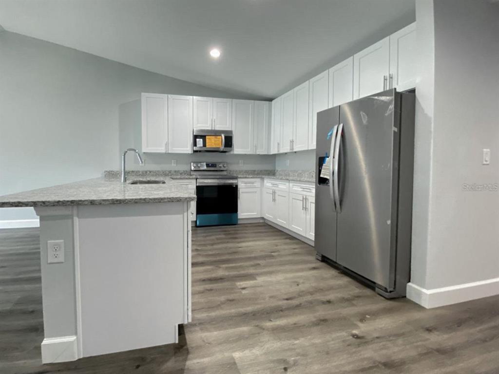 A kitchen features white cabinets, stainless steel appliances, and a granite-topped island — 9317 AGATE STREET UNIT 9317, PORT CHARLOTTE, FL