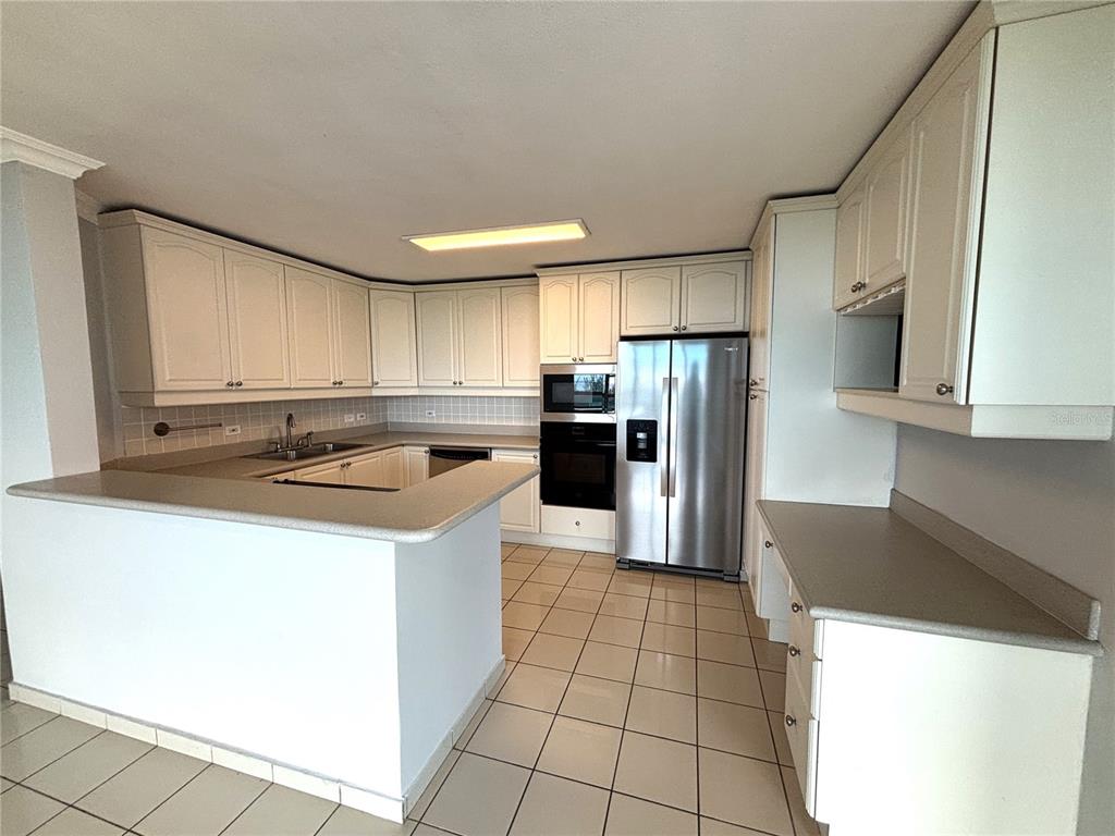A kitchen features white cabinets, stainless steel appliances, a breakfast bar, and tiled flooring — 550 Avenida Constitucion AVENIDA CONSTITUCION UNIT 901, SAN JUAN, PR