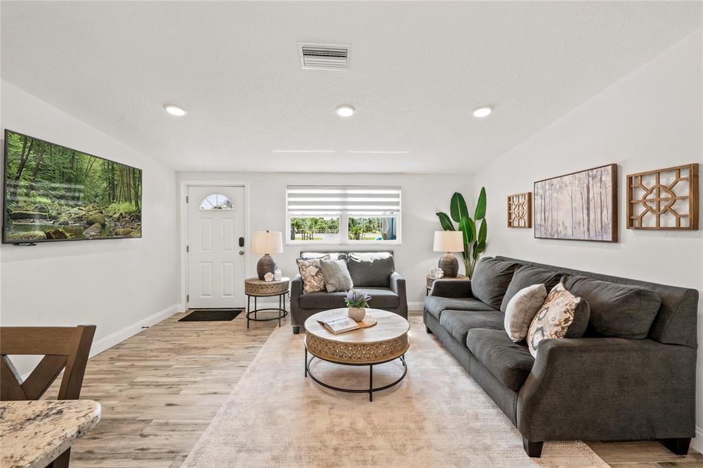 A modern kitchen features white cabinets, granite countertops, a farmhouse sink, and a breakfast bar — 749 N SR 415, OSTEEN, FL