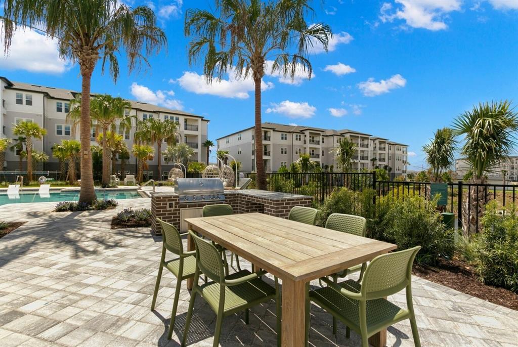 An outdoor patio features a wooden dining table, green chairs, and a built-in brick grill — 1310 RIDGEVIEW CIRCLE UNIT A1, DAVENPORT, FL
