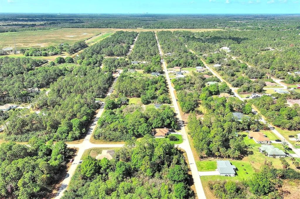 An aerial view shows a rural residential area with houses scattered among dense trees — 3201 49TH STREET W, LEHIGH ACRES, FL