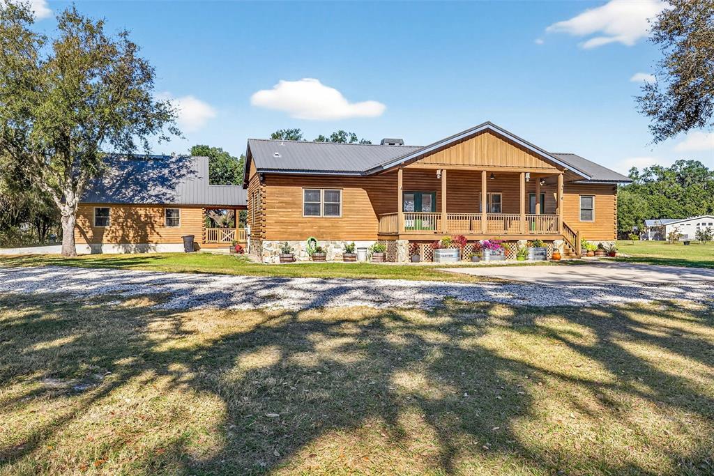 A wooden cabin with a metal roof and a covered front porch sits on grass — 6750 SUTTON OAKS LANE, ZEPHYRHILLS, FL